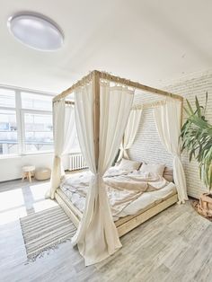 a bedroom with white walls and wooden flooring has a four poster bed covered in drapes