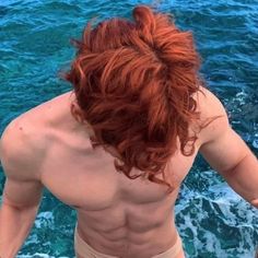 a man with red hair standing on a boat in the ocean looking down at the water