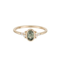 a gold ring with an oval green and white stone in the center, surrounded by small diamonds