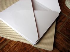 two white envelopes sitting on top of each other next to a cup and saucer