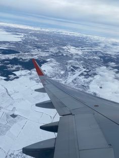 the wing of an airplane flying over snow covered land