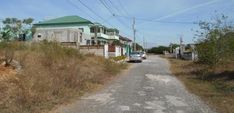 a car parked on the side of a dirt road next to houses and power lines