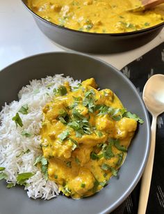 a plate with rice and curry on it next to a bowl filled with white rice