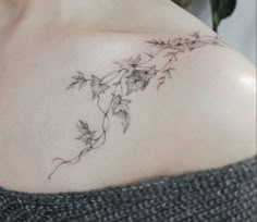 a woman's shoulder with flowers and leaves tattoo on her left side ribcage