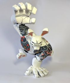 a white and black cat figurine with its arms in the shape of a rabbit