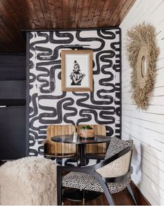 two chairs and a table in front of a wall with black and white designs on it