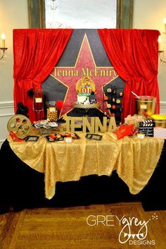 the table is set up for a movie themed birthday party with red curtains and decorations