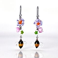 a pair of earrings with flowers and acrylic beads hanging from it's hooks