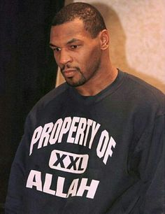 the man is wearing a black sweatshirt that says property of allah on it and has his hands in his pockets