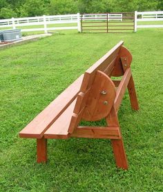 a wooden bench sitting on top of a lush green field next to a white fence