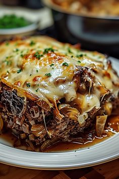 a white plate topped with lasagna covered in cheese and sauce on top of a wooden table