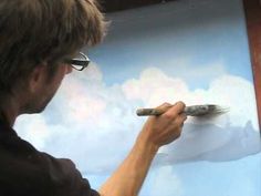 a man is painting clouds with a brush