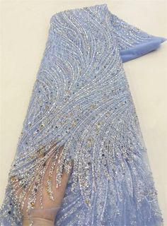 a woman's hand holding onto a blue dress with sequins on it