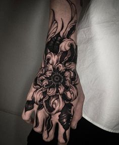 a black and white tattoo on the hand of a person with an intricate flower design