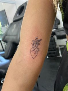 a person with a tattoo on their arm holding a flower in the shape of a heart