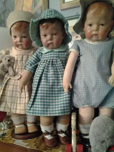 three antique dolls are standing next to each other