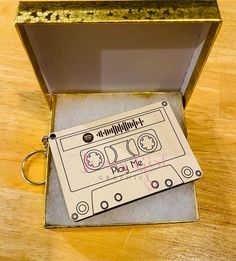 an old fashioned cassette tape keychain in a metal box on a wooden table