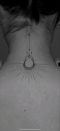 the back of a woman's neck with an arrow and sun tattoo on it