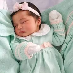 a baby girl is sleeping in her crib wearing a green dress and white bonnet