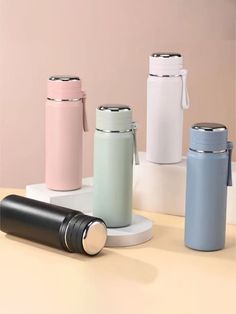 thermos are lined up next to each other in different colors and sizes on a table