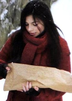 a woman holding a large piece of wood in her hands while walking through the snow