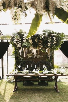 an outdoor dining table set up with flowers and greenery