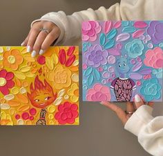 two women holding colorful cards with designs on them