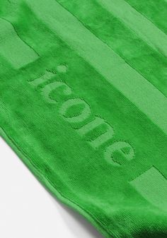 a green towel that has the word moto written on it and is laying on a white surface