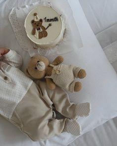 a baby's first birthday cake, teddy bear and diaper on a bed