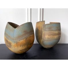 two vases sitting on top of a table next to each other, one has a brown and blue design