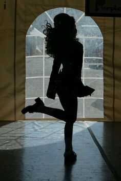 the silhouette of a woman dancing in front of an open door with her legs spread out