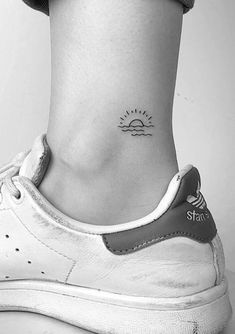 a black and white photo of a person's foot with a small tattoo on the ankle