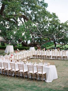 an outdoor wedding setup with tables, chairs and white tablecloths on the grass