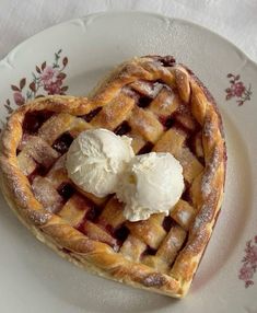 a heart shaped waffle with ice cream on top is sitting on a floral plate