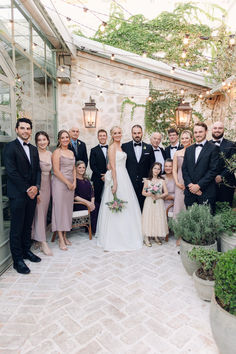 a group of people standing next to each other in front of a building with potted plants