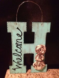 a wooden sign that says i love you and has flowers on the letter h in front of it