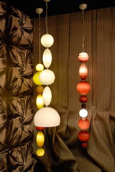 several different colored lights hanging from the ceiling in front of a brown curtain and drapes