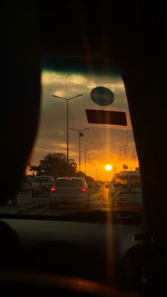 the sun is setting behind some cars in traffic