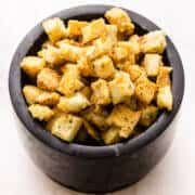 a black bowl filled with cubed food on top of a table