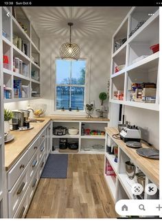 a kitchen with lots of white cabinets and wood flooring on the counter top, next to a window