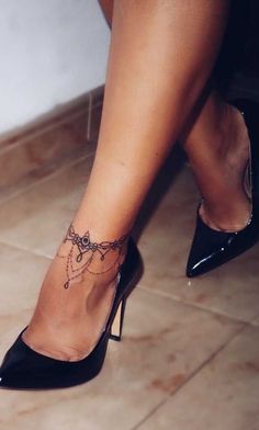 a woman's legs with a tattoo on her left leg and heels in the foreground