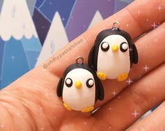 two small penguins are sitting on top of someone's finger and they look like they have eyes