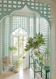 a green bench sitting under a window next to a potted plant