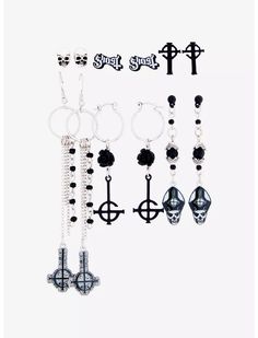 six pairs of black and white earrings hanging from hooks with cross charms attached to them