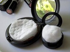 an open compact mirror sitting on top of a table next to a powdered container