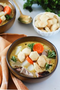 two bowls filled with soup and vegetables on top of a table