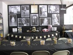 a black table with pictures on the wall and some chairs in front of it at a party