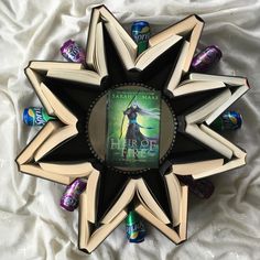 an open book on top of a star shaped object with candy in the bottom corner