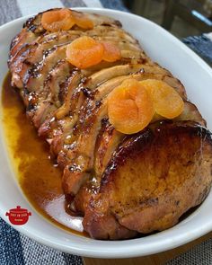 a white plate topped with meat covered in gravy and sliced orange wedges