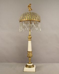 a white and gold table lamp with crystal chandelier on the top of it